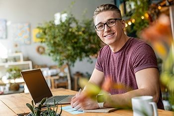 Young-man-smiling-in-front-of-laptop